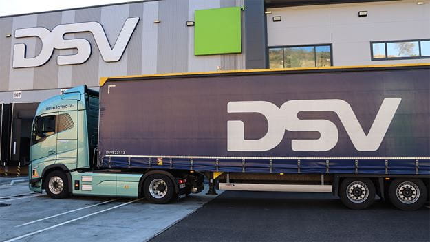 Un camión 100% eléctrico de DSV estacionado en un centro logístico moderno.