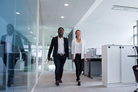 homem e mulher caminhando em um corredor de escritorio