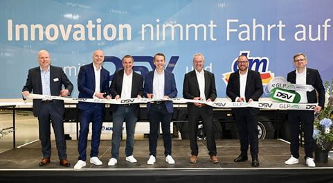 Männer auf Bühne schneiden Eröffnungsband durch