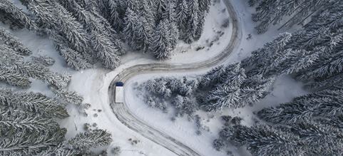 Rekka ajaa lumisella tiellä lumisen metsän keskellä.