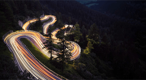 Recorridos en una carretera entre el bosque, marcados por haces de luces.