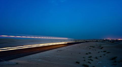 Carretera entre arena durante la noche, con el camino recorrido marcado con haces de luces. | DSV