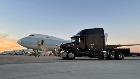 Camión de DSV junto a un avión de carga, estacionados en la pista durante el atardecer.