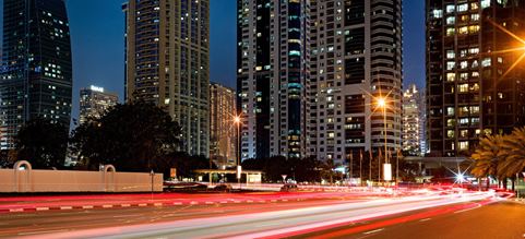 Carretera entre edificios en los Emiratos Árabes, con haces de luz representando velocidad.