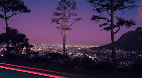 Carretera con vista a la ciudad durante un atardecer morado. 