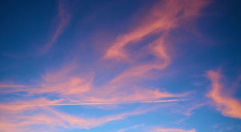 Red clouds and contrails after a plane in the sky