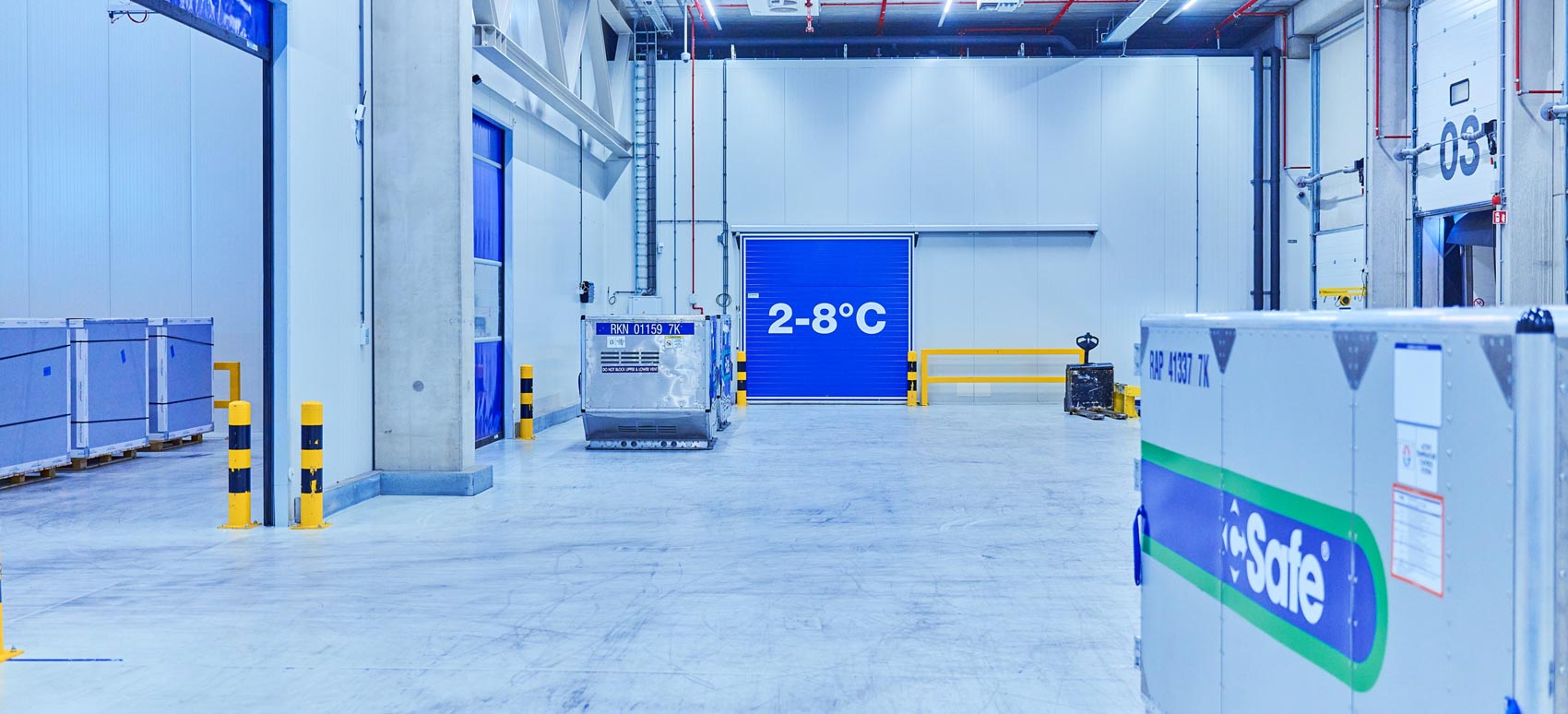 Temperature-controlled warehouse interior with insulated containers and safety barriers, featuring a cold storage area marked 2–8°C for sensitive goods.