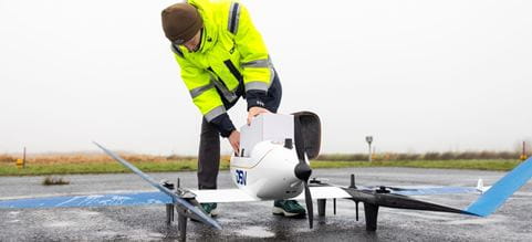 Mann med gul jakke som laster en DSV drone
