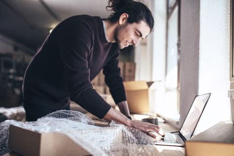 Young man working on laptop with parcel on the side. 