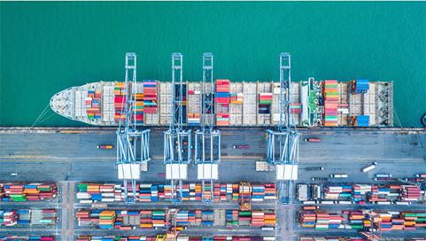 A cargo vessel unloading its cargo at a dockyard.