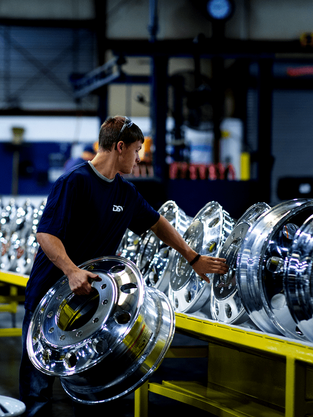 man handling car rims in a warehouse