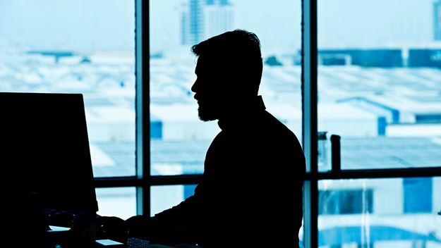 A man is front of the computer in the office