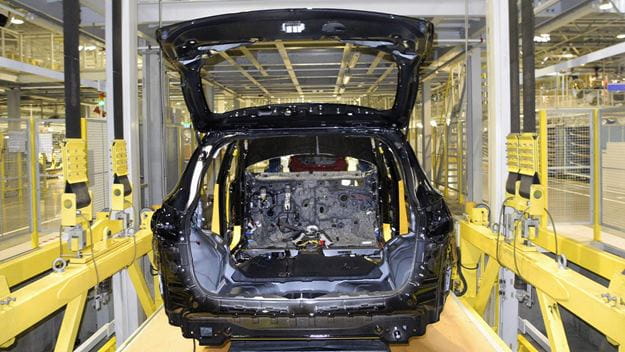 Car on assembly line with open trunk