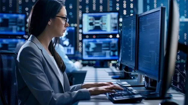 A woman sitting in front of a computer monitor