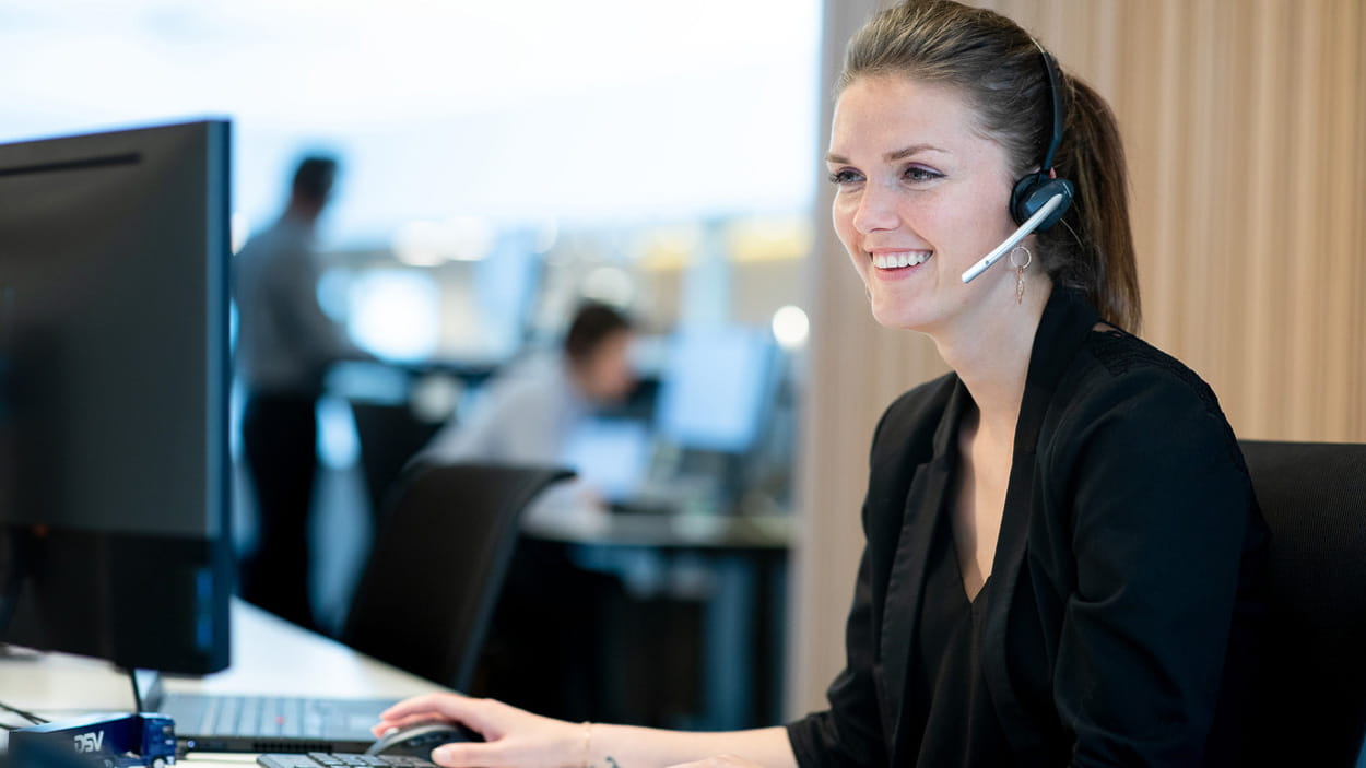 Frau am Computer mit Headset