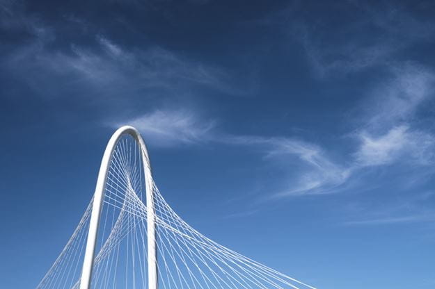 Blauer Himmel mit weißer, geschwungener Brücke