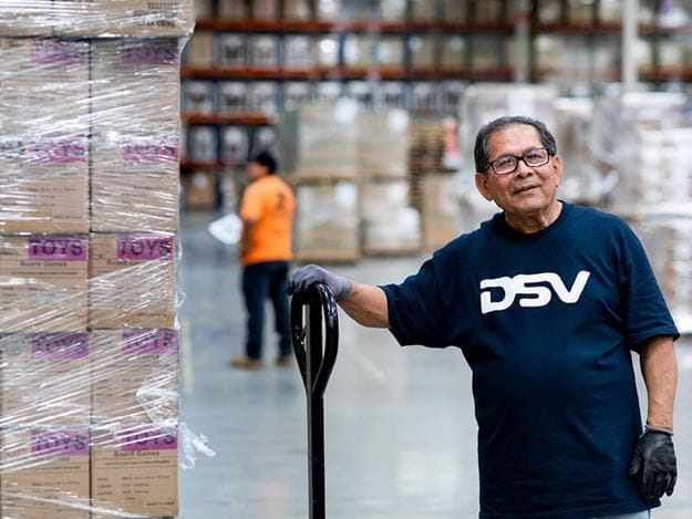 DSV medarbejder står ved en palleløfter på lager