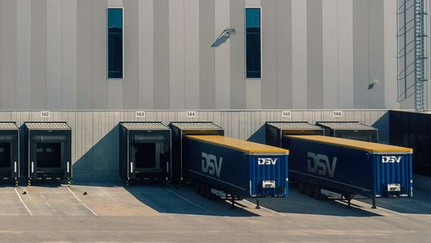 Varios remolques de DSV están alineados en los muelles de carga de un moderno centro logístico.