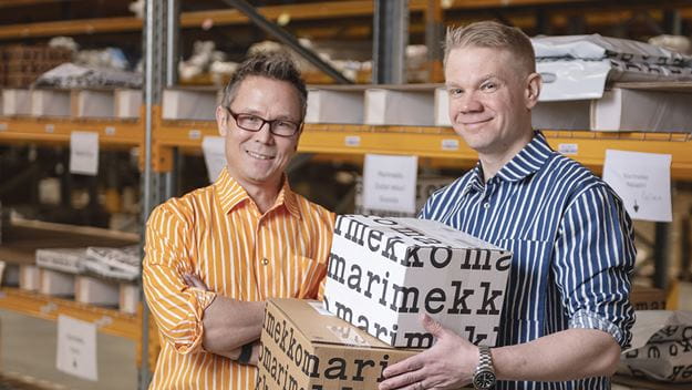 DSV:n myyntojohtaja Toni Palmumaa ja Marimekon logistiikkajohtaja Ville pitkänen hymyilevät Marimekko-paidat päällään DSV:n varastossa.