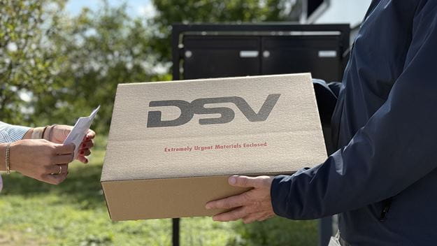 Henkilö pitää käsissään DSV-logollista pakettia ja ojentaa sen toiselle henkilölle.