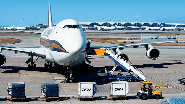 Cargo plane parked at an airport with containers on dollies positioned for loading