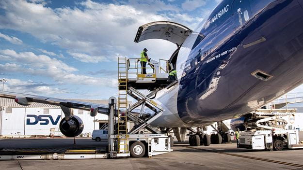 Cargo aircraft being loaded using a lifting platform, with ground crew handling freight.