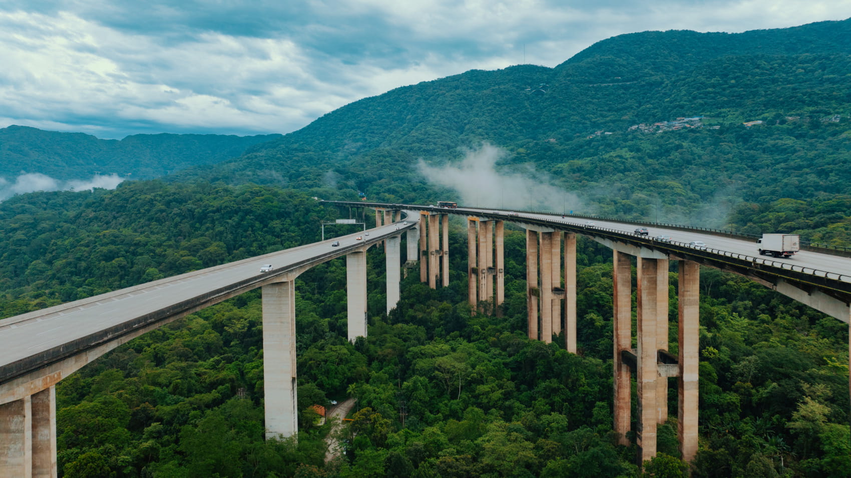 Highway bridge spanning a forested valley, supporting steady cargo and road transport across elevated terrain