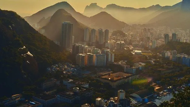 Hazy cityscape nestled in mountains under golden light.