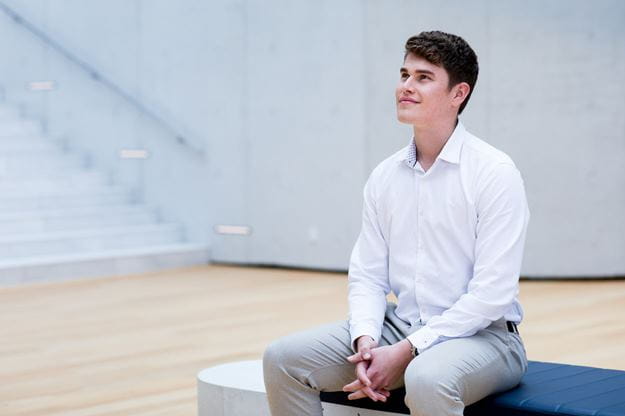 Male trainee sitting in the atrium in the DSV headquarter in Hedehusene