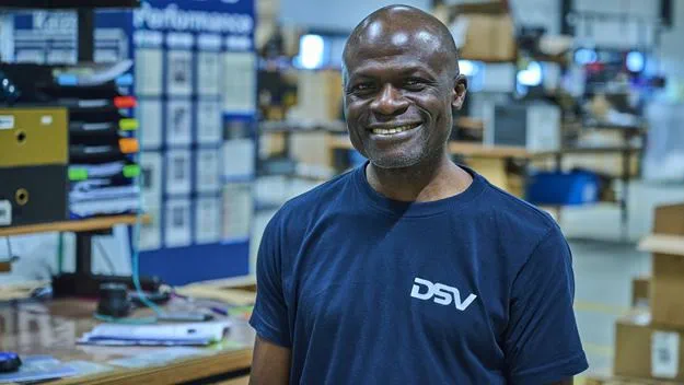  A smiling man in a DSV shirt is in a warehouse.