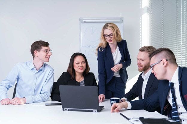 Five DSV employees sitting in a conference room pointing at a computer screen