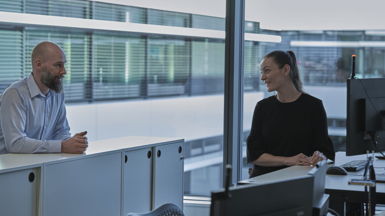 Un homme et une femme discutent dans un bureau moderne.