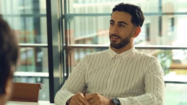 A man with a striped shirt is in a meeting.