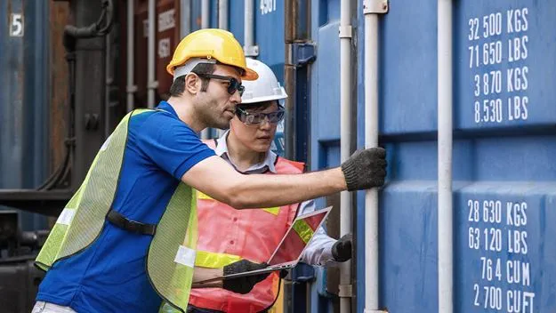 Two foreman with laptop opening containers box door checking products from cargo freight ship at cargo container shipping.