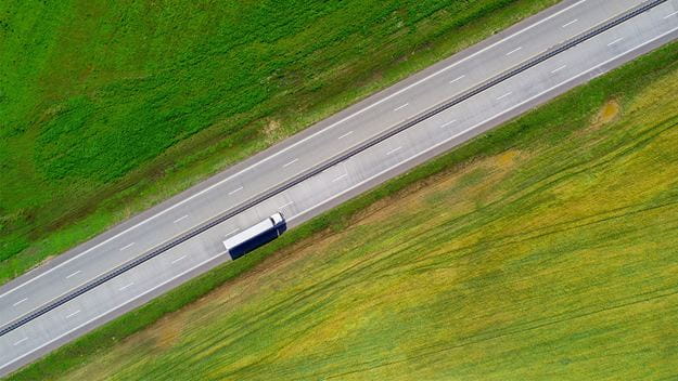 Camión de carga blanco de DSV en una carretera con paisaje verde.