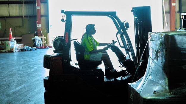 Warehouse worker moving goods in a forklift