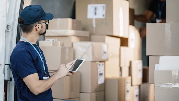 Modern delivery -Driver using mobile phone to manage packages in a delivery truck.