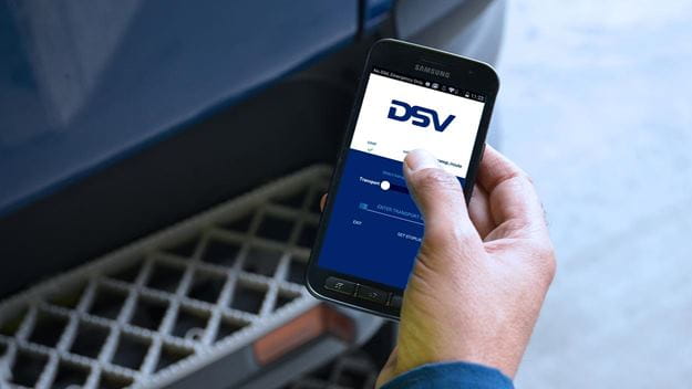 Hand holding smartphone displaying the DSV mobile app for transportation management.