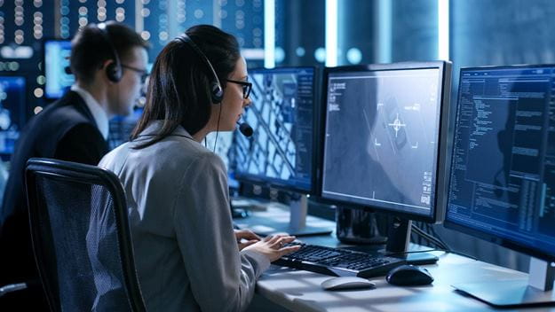 Uma mulher e um homem trabalhando em laptops olhando para a tela