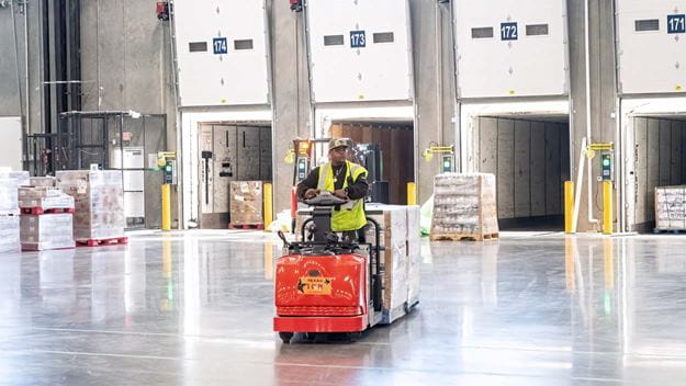 Warehouse worker unloading trailers at dock inside warehouse