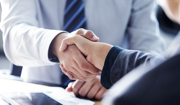 Un apretón de manos entre dos profesionales en un entorno empresarial, simbolizando un acuerdo exitoso o una nueva colaboración.