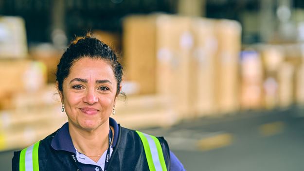 Warehouse employee wearing a high-visibility vest standing in front of stacked cargo boxes