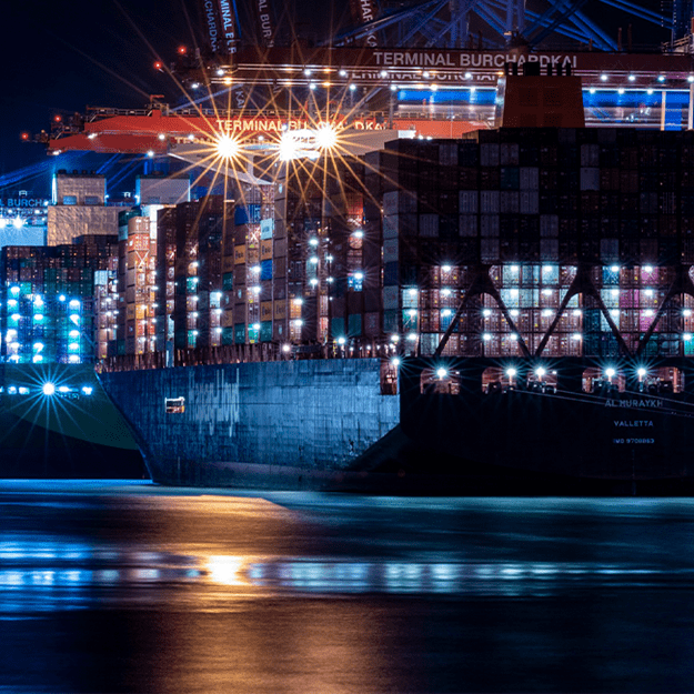 Close-up view of a container ship docked at night, fully loaded with shipping containers stacked high