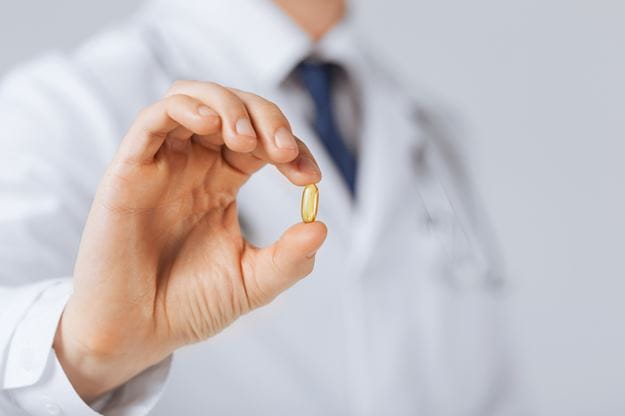 Medical doctor displaying pharmaceutical capsule between fingers