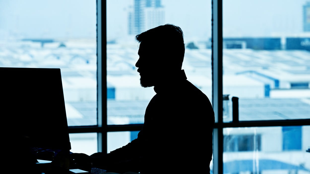  A person wearing a DSV shirt works at a computer.
