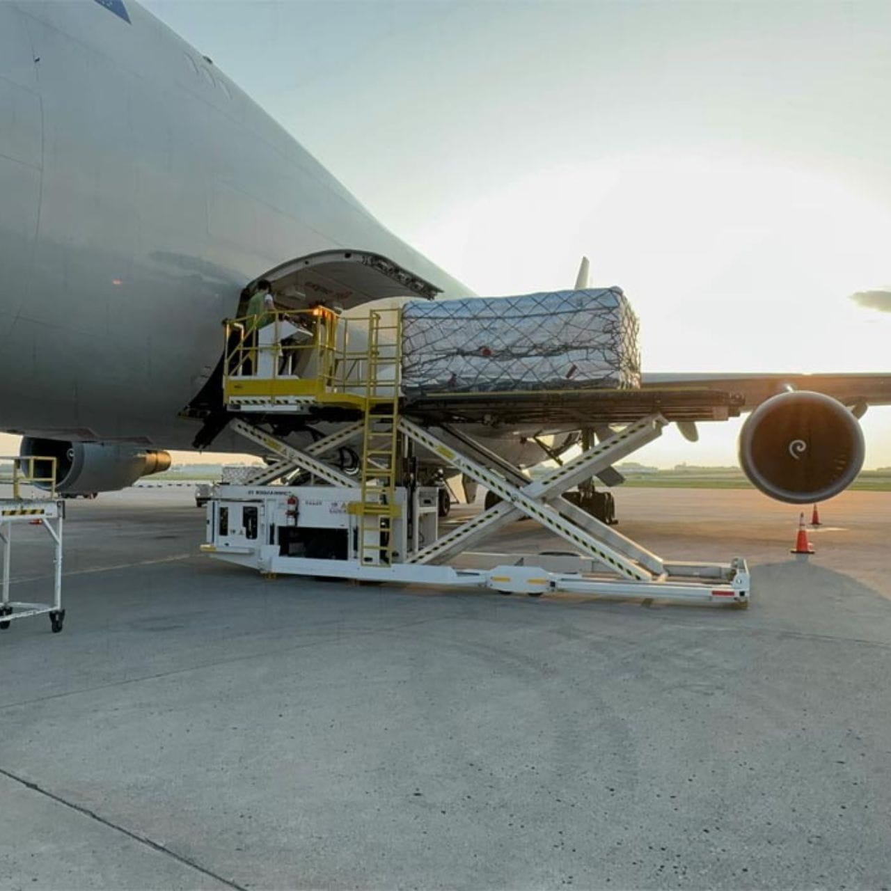 Cargo aircraft being loaded on the apron using a scissor lift, with palletised freight positioned at the cargo door