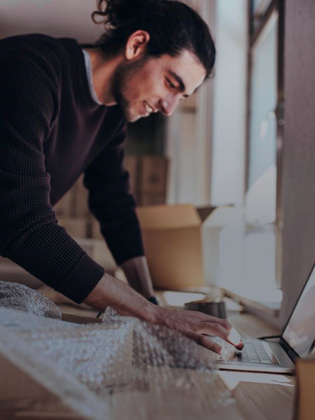 En person vises som bruker en bærbar PC etter å ha pakket ut pappeskene.