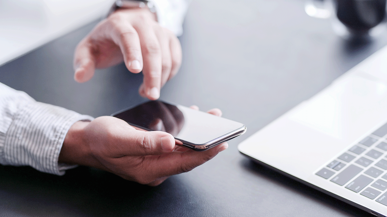 Smartphone nella mano di un uomo mentre l'altra mano lo sta prendendo
