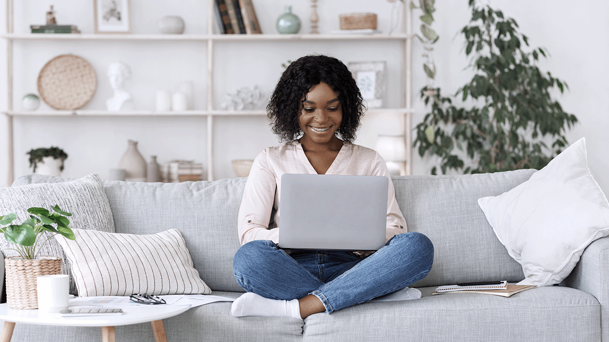 Donna seduta su un divano con il suo computer portatile