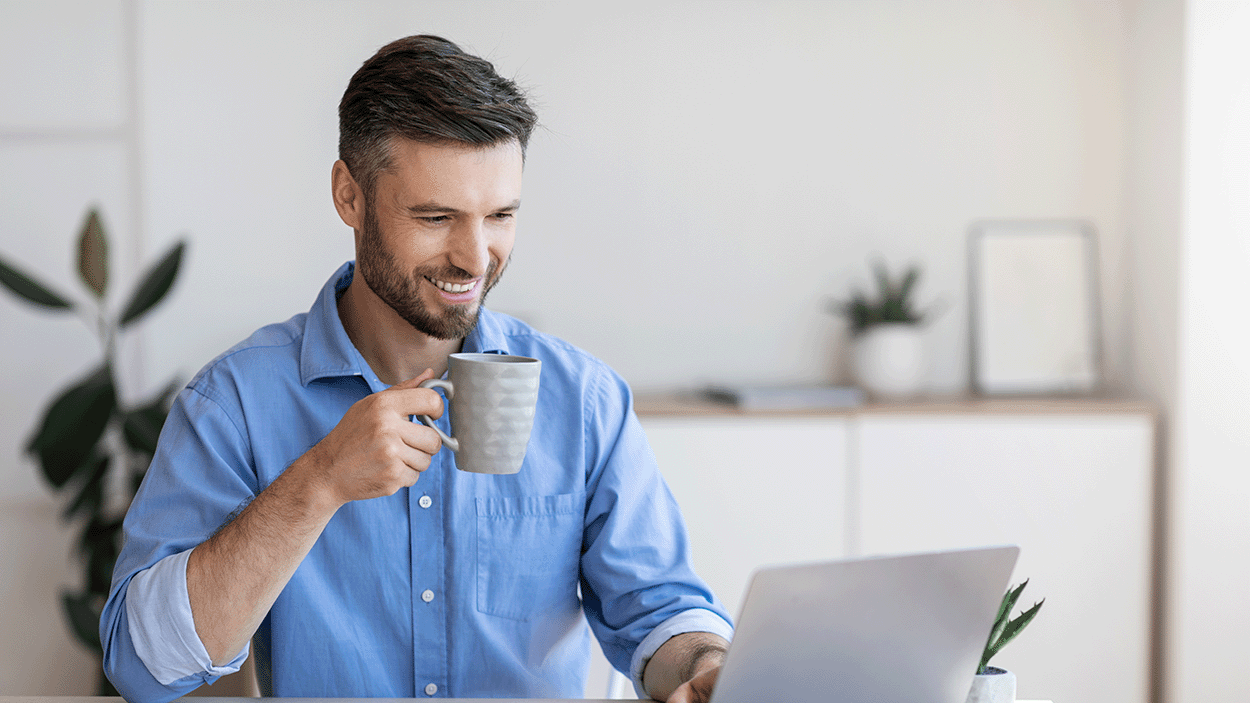 Uomo che beve caffè davanti al suo computer portatile